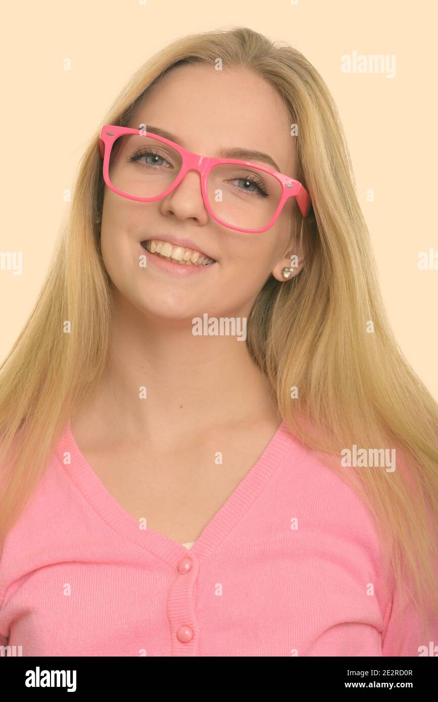 Face of young happy teenage girl smiling while wearing pink eyeglasses Stock Photo