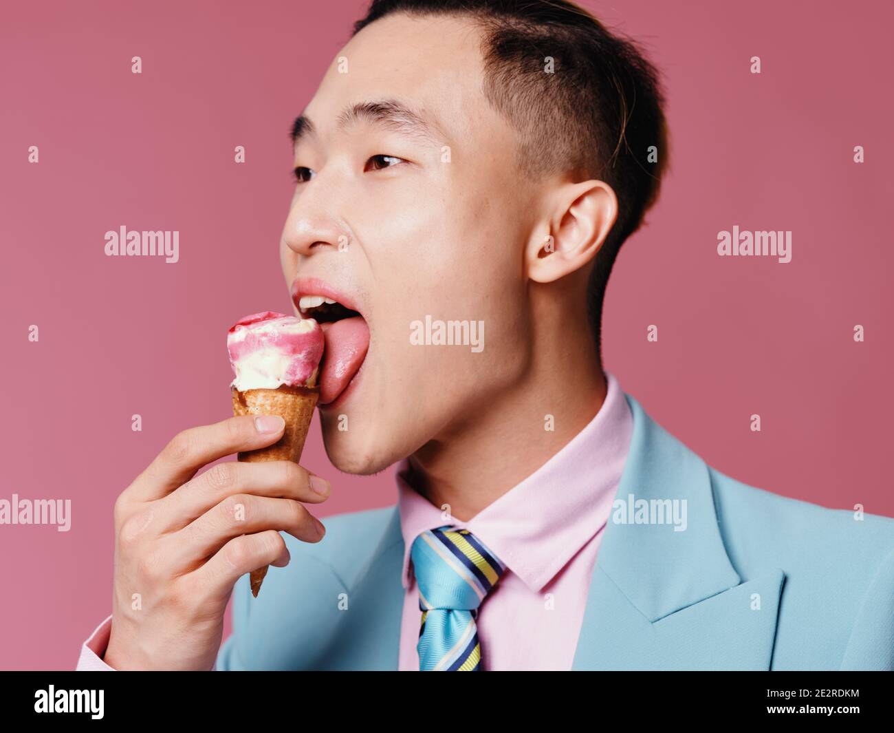 Happy Asian man licks ice cream on pink background Stock Photo Alamy