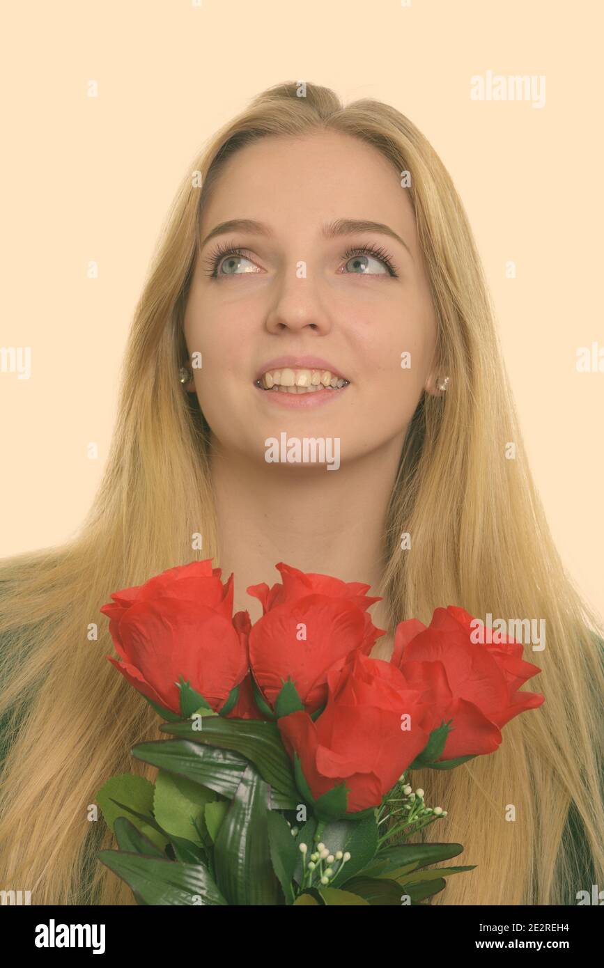 Face of thoughtful happy teenage girl smiling while holding red roses ...