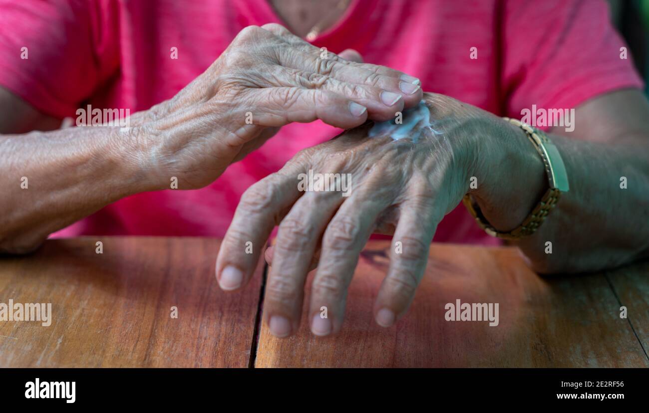 Wrinkled hands putting cream on their skin Stock Photo