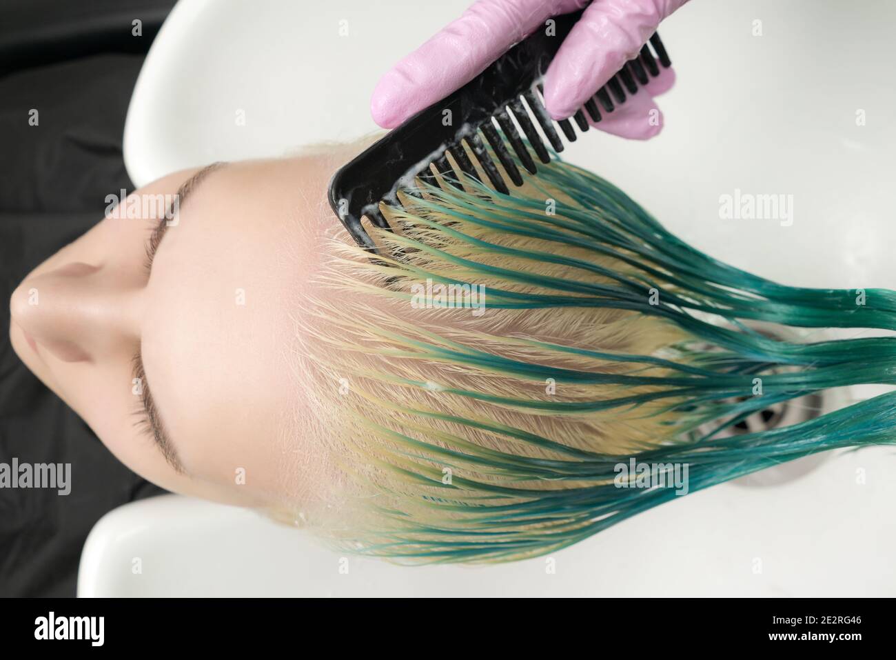 Top view of hairdresser holding wet hair in hand and combing young woman  long green and discolored hair, while shampooing in shower in white sink  Stock Photo - Alamy