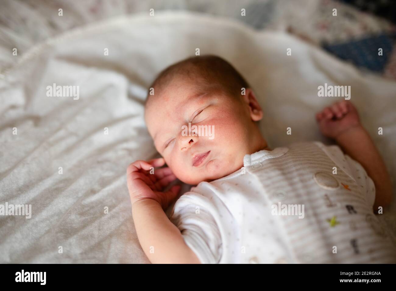 Newborn baby for the first time at home, lying in a blanket on the bed