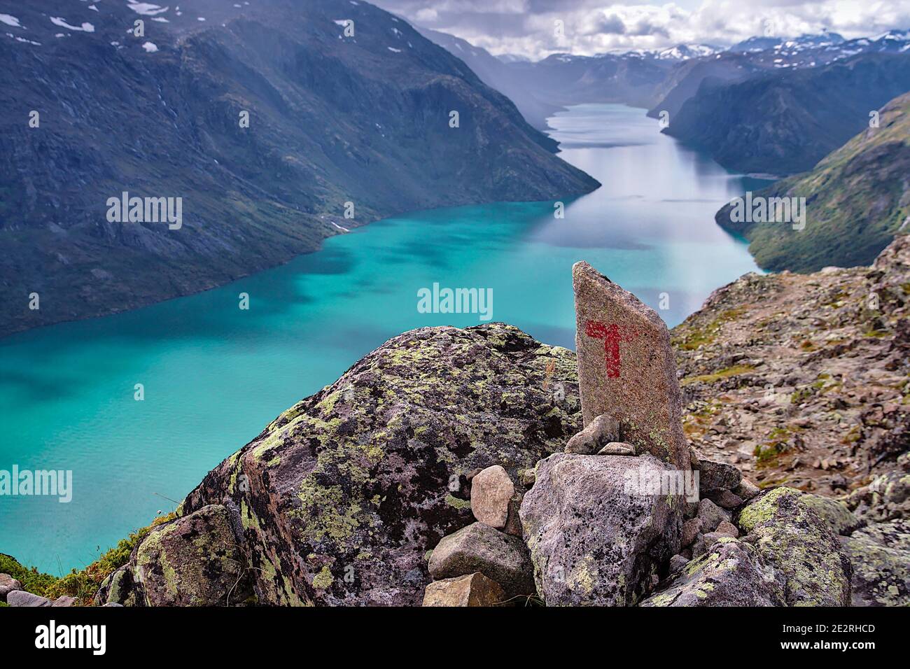The red T marking the path at Bessegen Ridge with the blue glacial Gjende Lake in the background, Norway Stock Photo