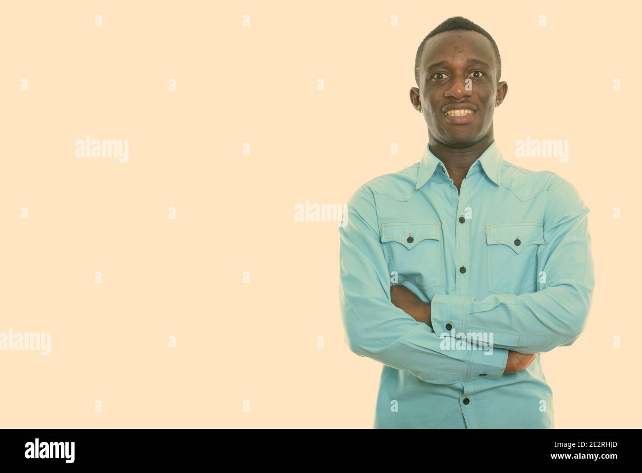 Studio shot of young happy black African man smiling with arms crossed ...