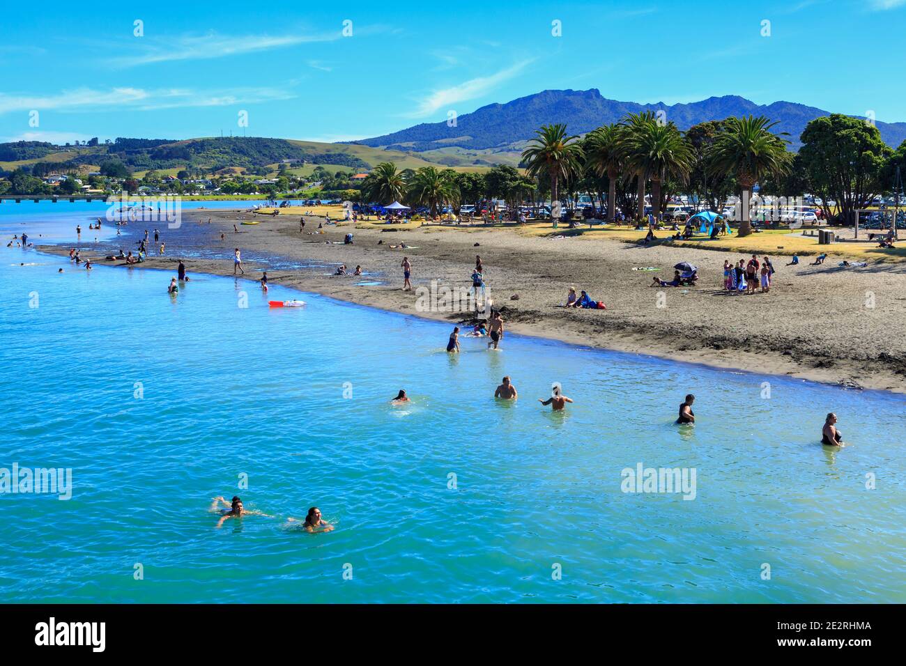 Te Kopua beach, Raglan, New Zealand, in summer, with people swimming and sunbathing Stock Photo