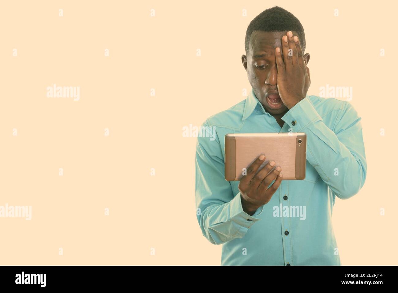 Studio shot of young black African man using digital tablet while ...