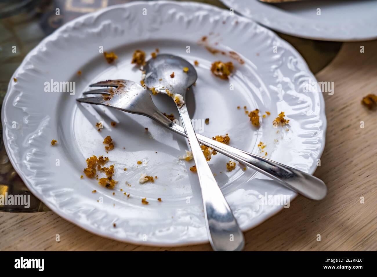 Empty dirty plate with spoon and fork on the table after breakfast Stock Photo