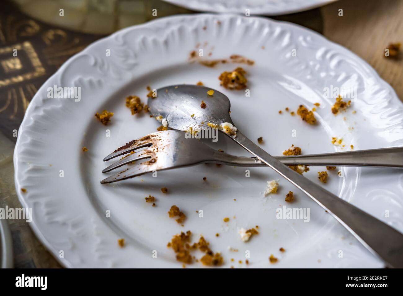Empty dirty plate with spoon and fork on the table after breakfast Stock Photo