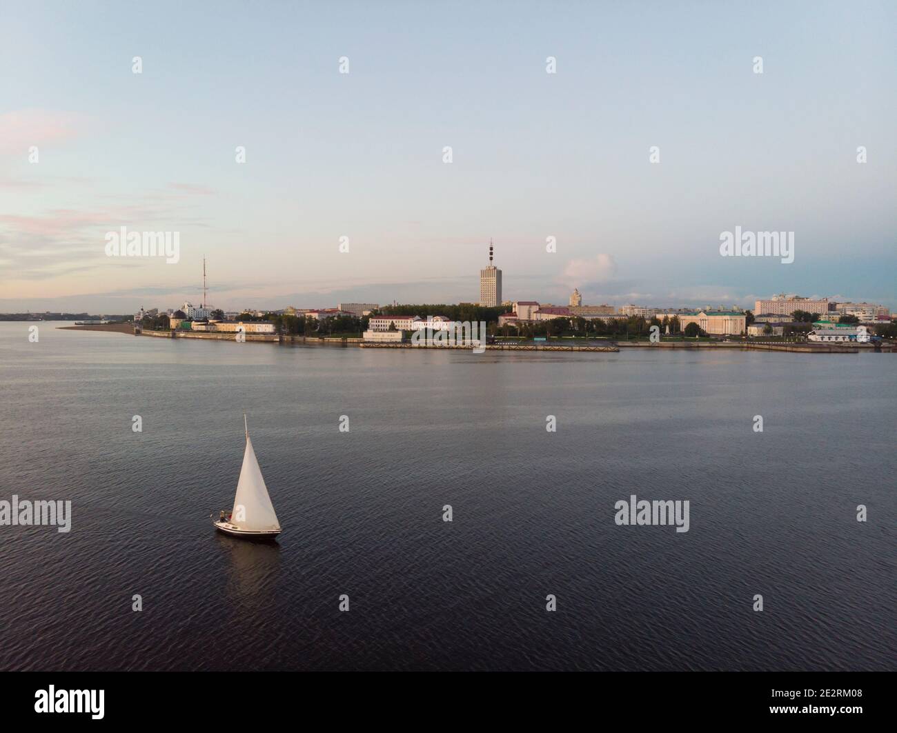 September, 2020 - Arkhangelsk. White yacht with a white sail on the background of the city of Arkhangelsk. Northern Dvina River. Arkhangelsk port. Rus Stock Photo