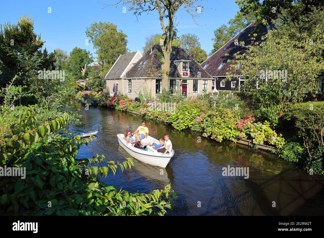 BROEK IN WATERLAND, NETHERLANDS - SEPTEMBER 13, 2020: A small town with traditional old wooden houses, with a Dutch family enjoying the canal by boat Stock Photo