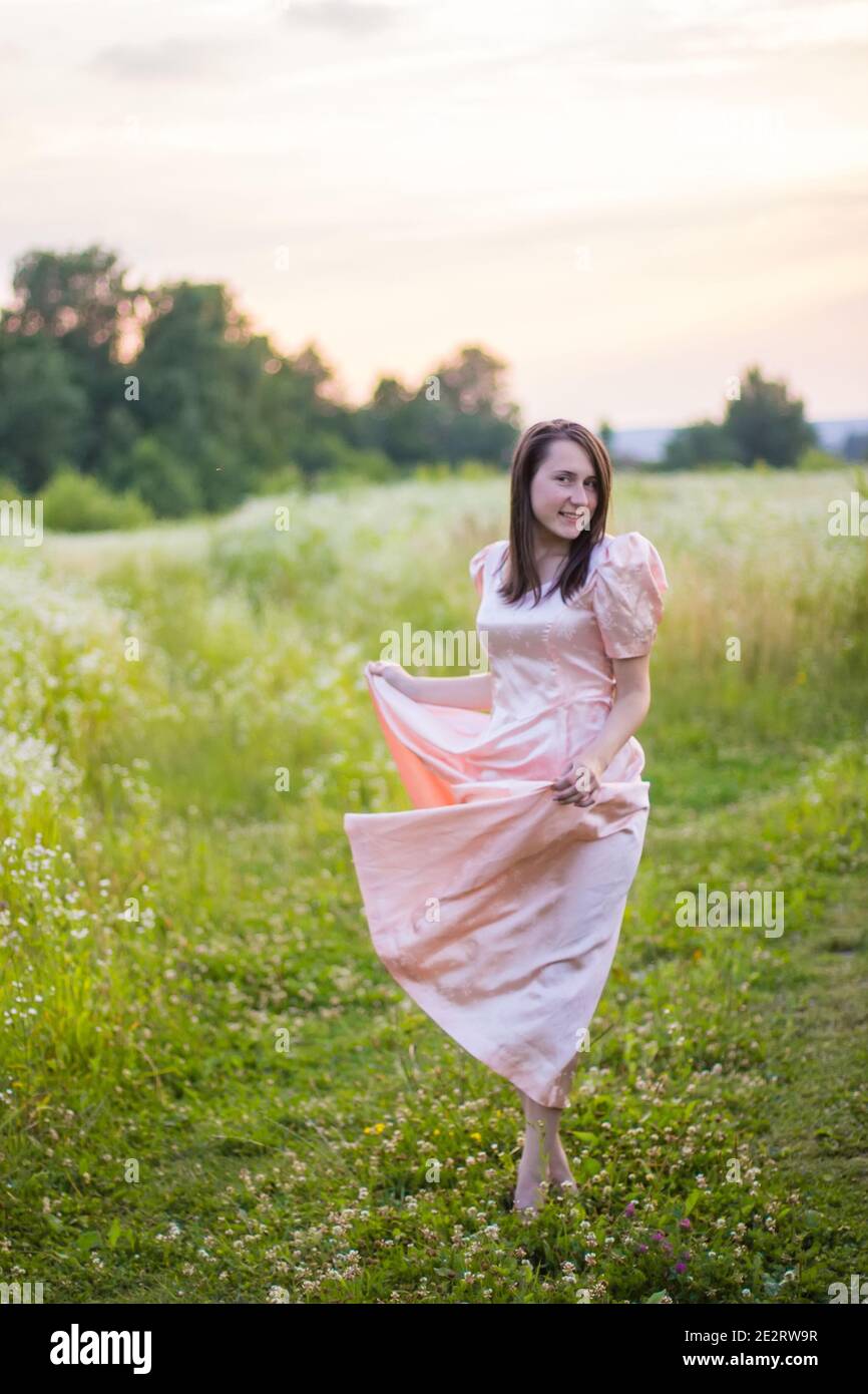 girl dancing in the field in a pink dress Stock Photo