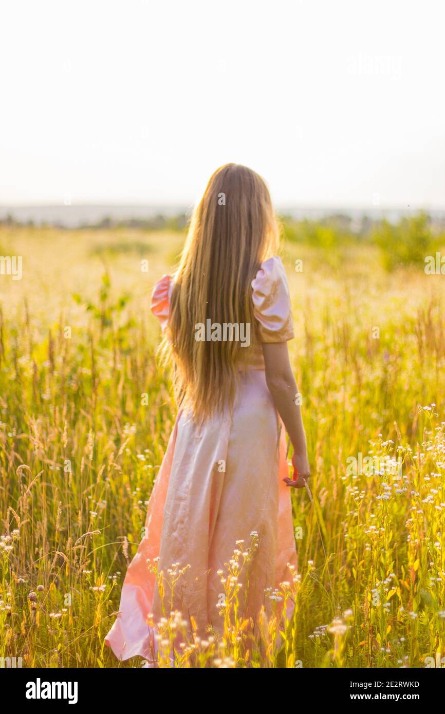 girl standing in the field in a pink dress Stock Photo - Alamy