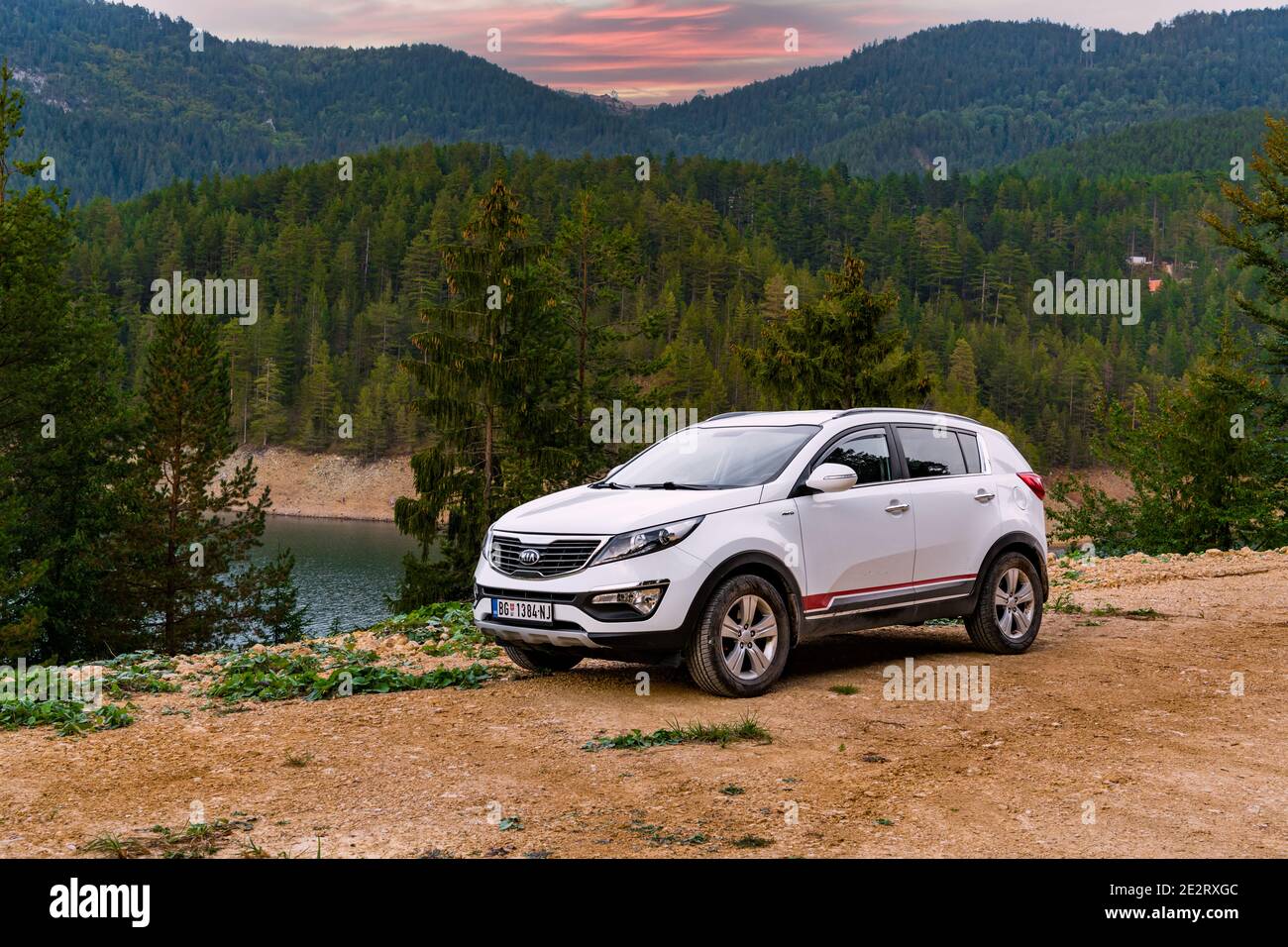 Kia Sportage 2.0 CRDI awd or 4x4, white color, parked in a dried coast lake Zaovine on mountain Tara. With a beautiful forest  in the background Stock Photo