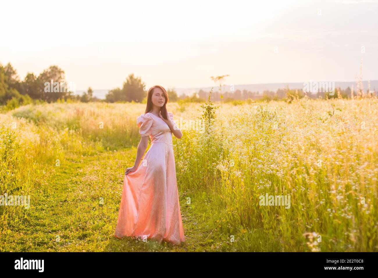 girl standing in the field in a pink dress Stock Photo - Alamy