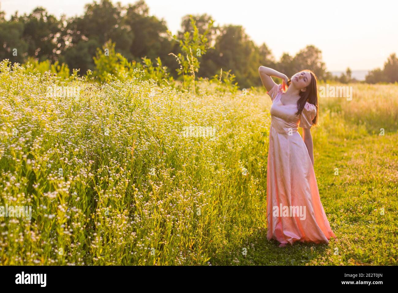 girl standing in the field in a pink dress Stock Photo