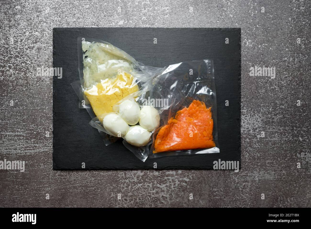 Products in vacuum packaging on black slate board. Boiled eggs and