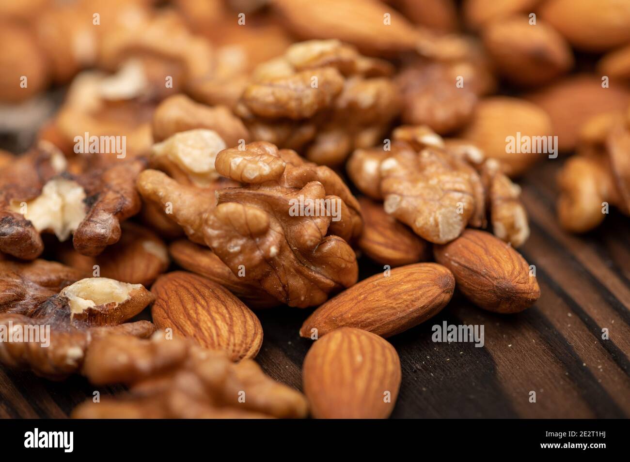Almonds and walnuts scattered on the table. Close-up, selective focus Stock Photo