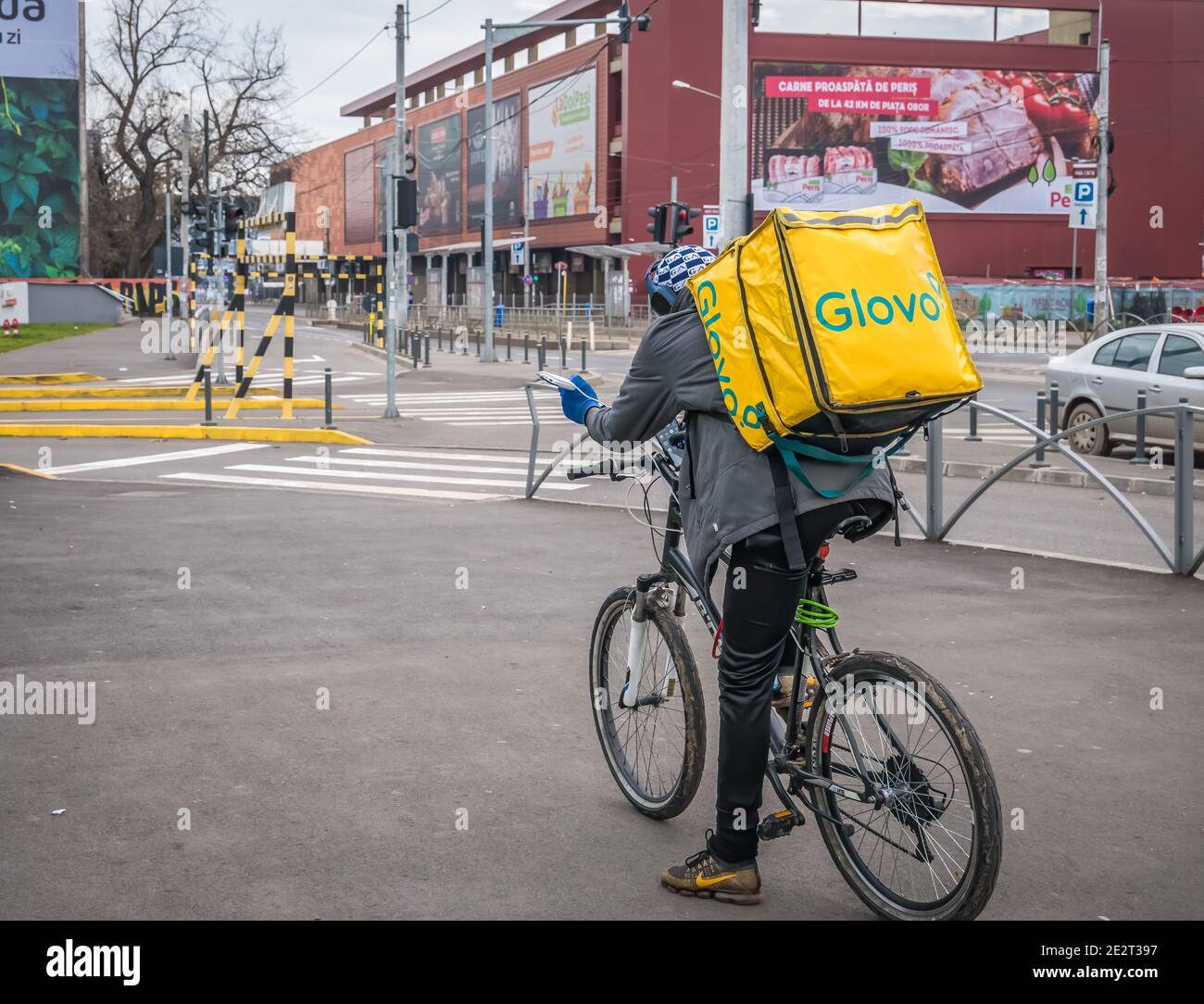 Bucharest/Romania - 12.25.2020: Glovo courier on a bicycle carrying the yellow delivery bag Stock Photo