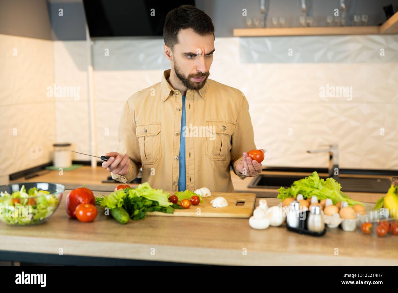 Young guy is curious about cooking vegetarian salad. Handsome man doesn ...