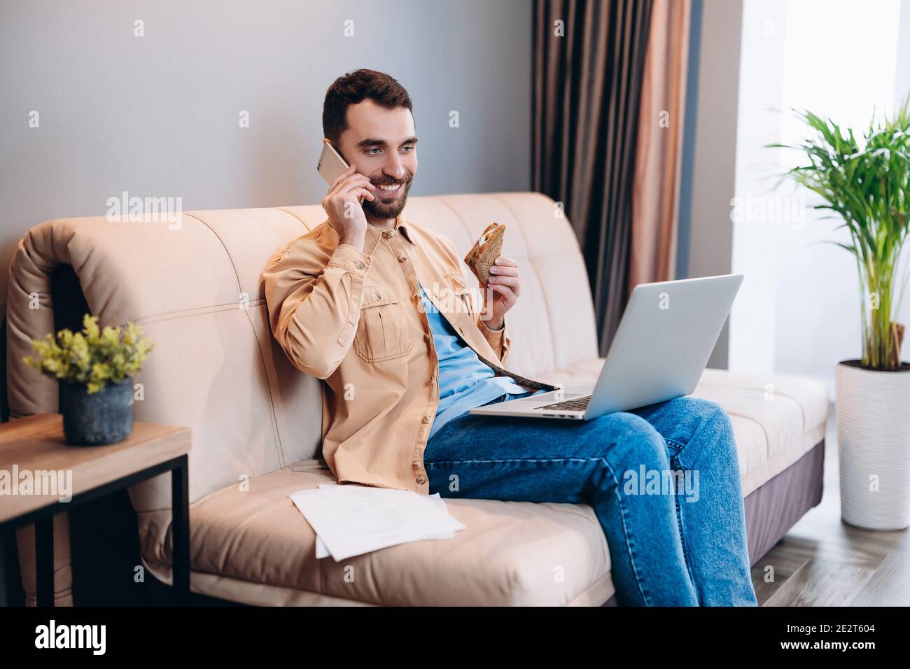 Remote work during lockdown concept. Happy male freelancer sits on sofa