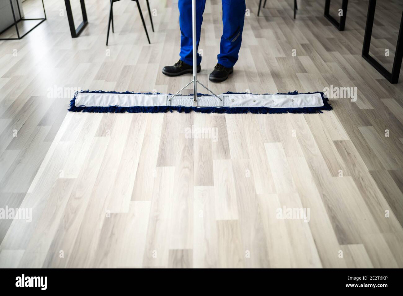 Male Janitor Mopping Floor In Face Mask In Office Stock Photo