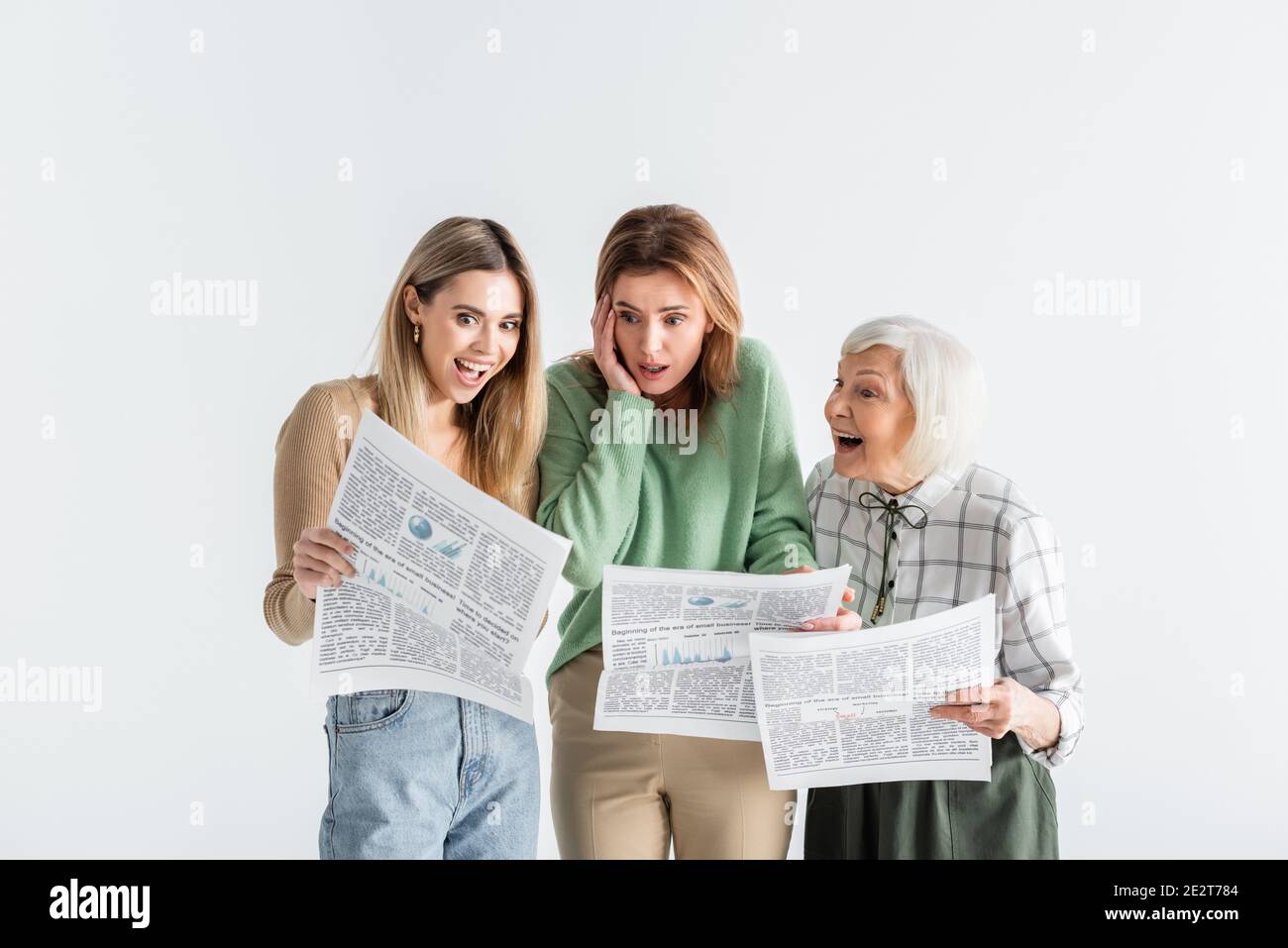 three generation of astonished women reading newspapers isolated on white Stock Photo