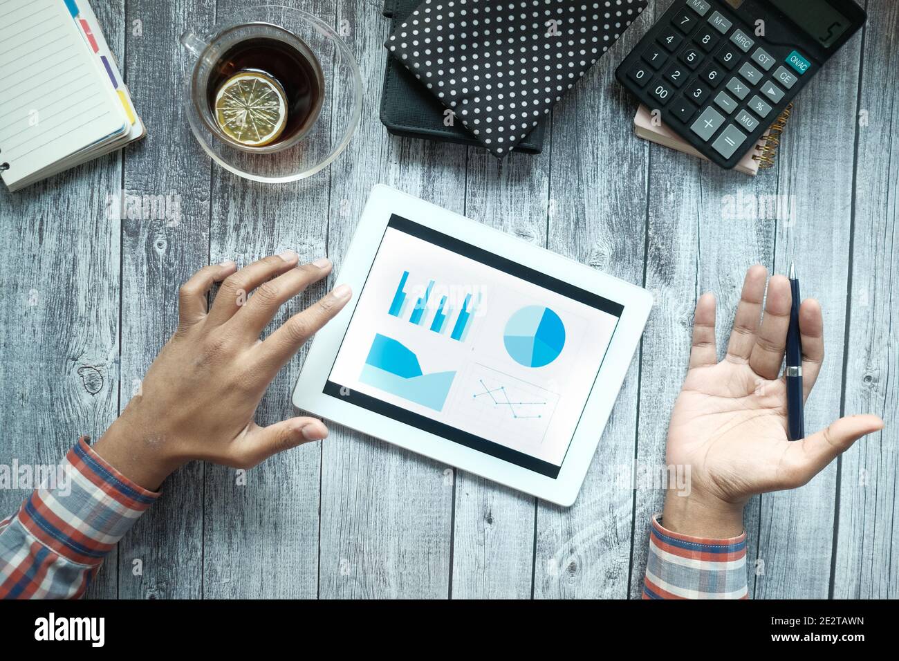 man's hand working on digital tablet at office desk, using self created chart  Stock Photo
