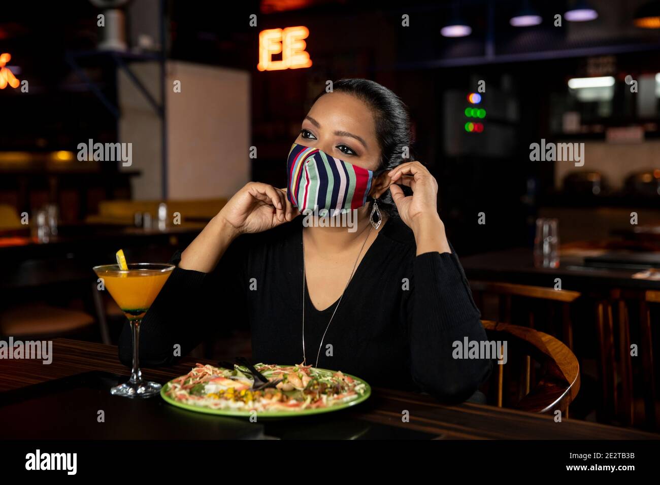 Portrait of a woman sitting in a restaurant while wearing Covid 19