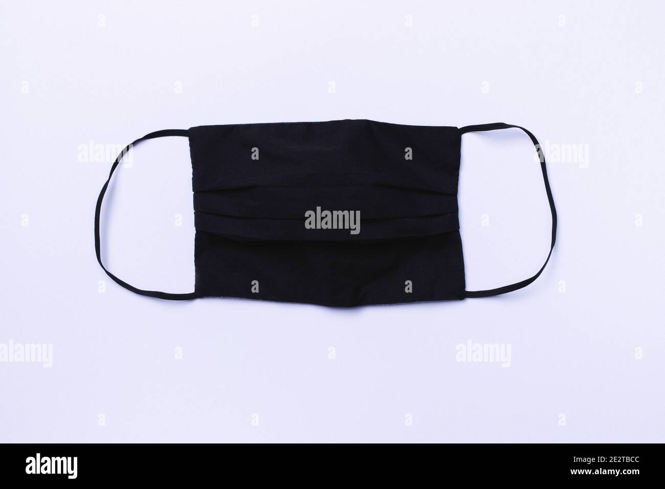 Coronavirus protective textile black face mask on a white background. Antiviral black cotton face mask during the COVID-19 pandemic virus. Stock Photo