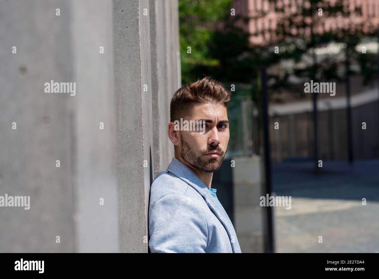 Bearded man leaning against wall and thinking Stock Photo