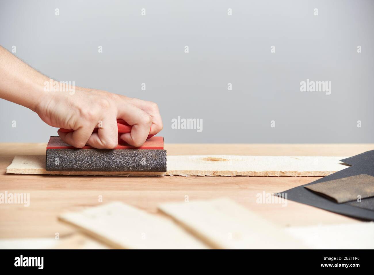 Detail of carpentry. Hand of a young woman sanding wood with sandpaper. Image with copy space. Stock Photo