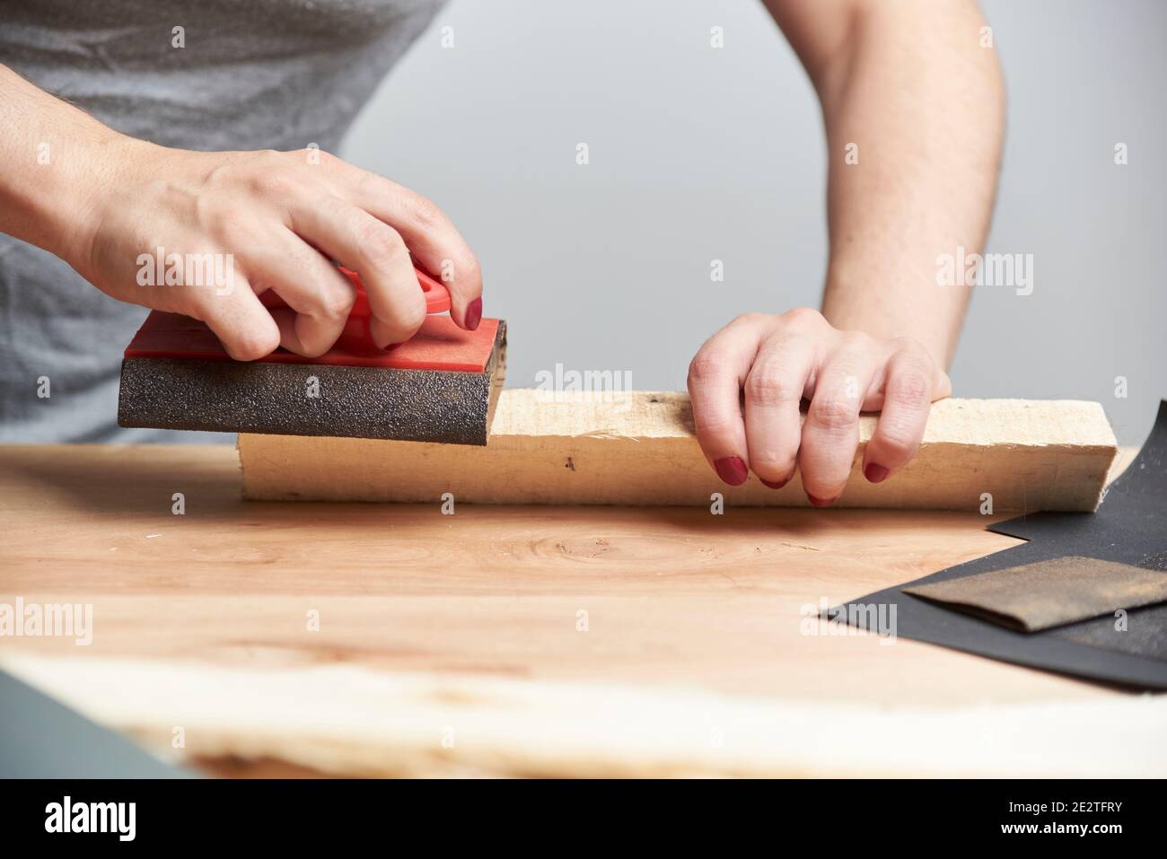 Woman fond of carpentry. Hands of a young woman with her nails done sanding wood with sandpaper. Stock Photo