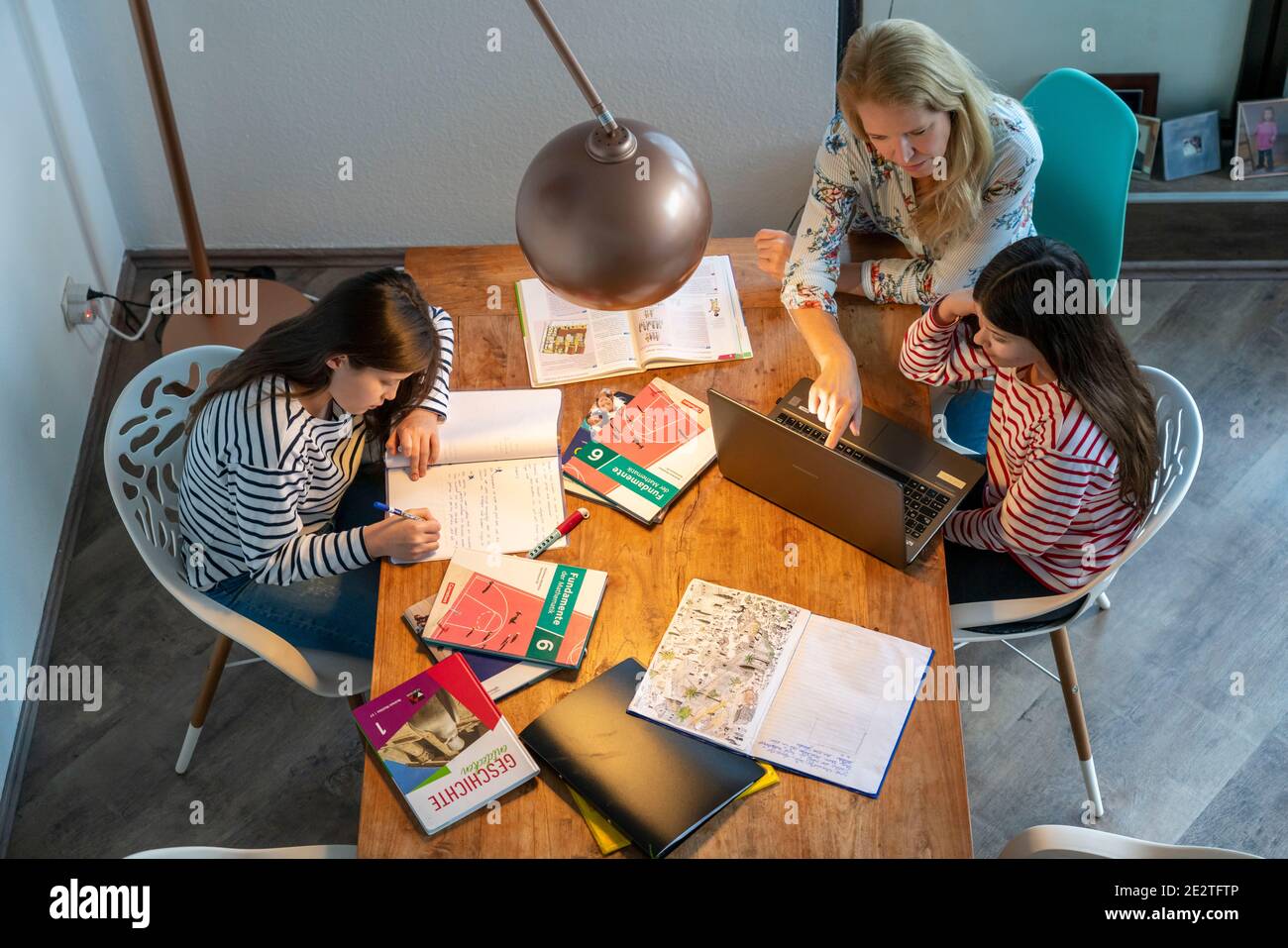 Homeschooling, during the lockdown in January 2021, mother helps her two daughters, at home, to learn, with textbooks and computers, school closures, Stock Photo