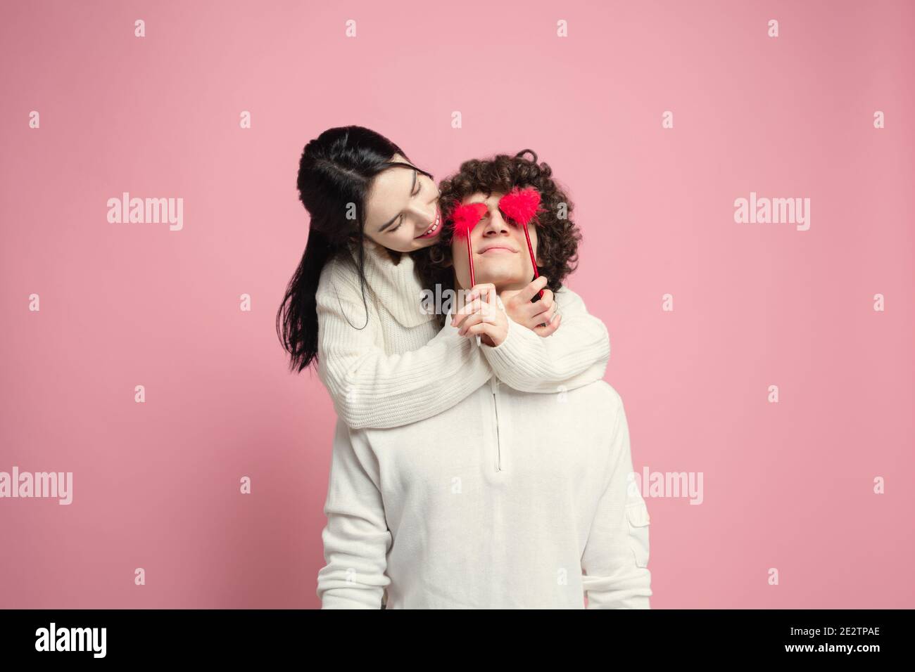 Young, beautiful couple in love on pink studio background. Saint