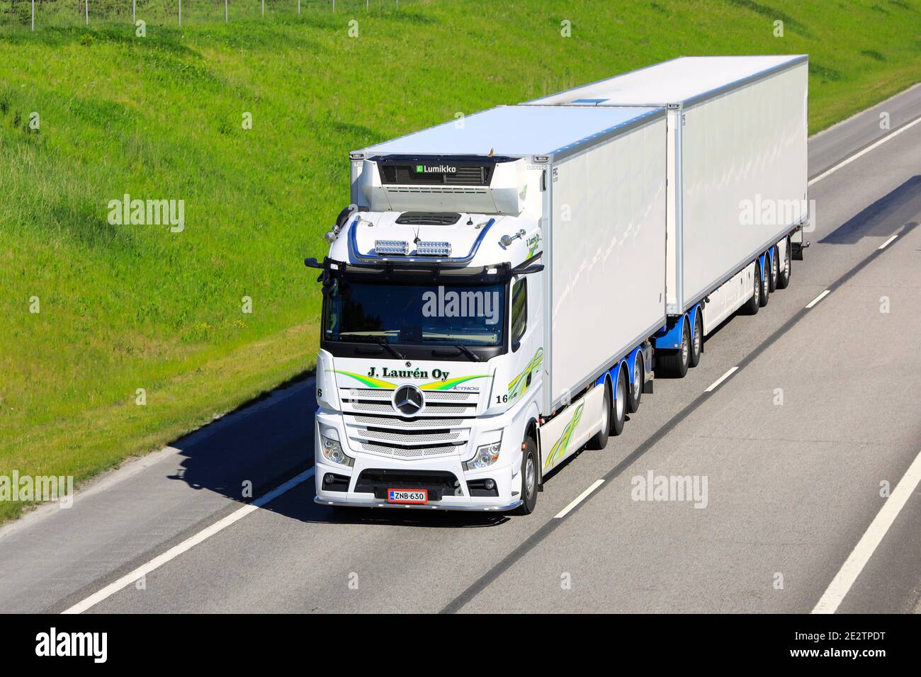 White Mercedes-Benz Actros transports goods in FRC trailer along freeway on a beautiful day of summer, elevated view. Salo, Finland. June 12, 2020. Stock Photo