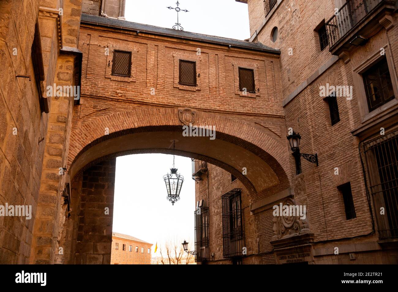 A delicate Christian iron cross atop the Toledo Cathedral Arch brick