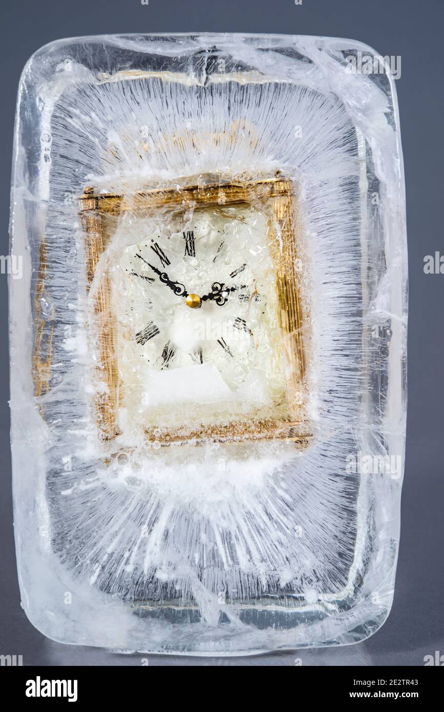 An old analogue clock frozen in a block of ice Stock Photo