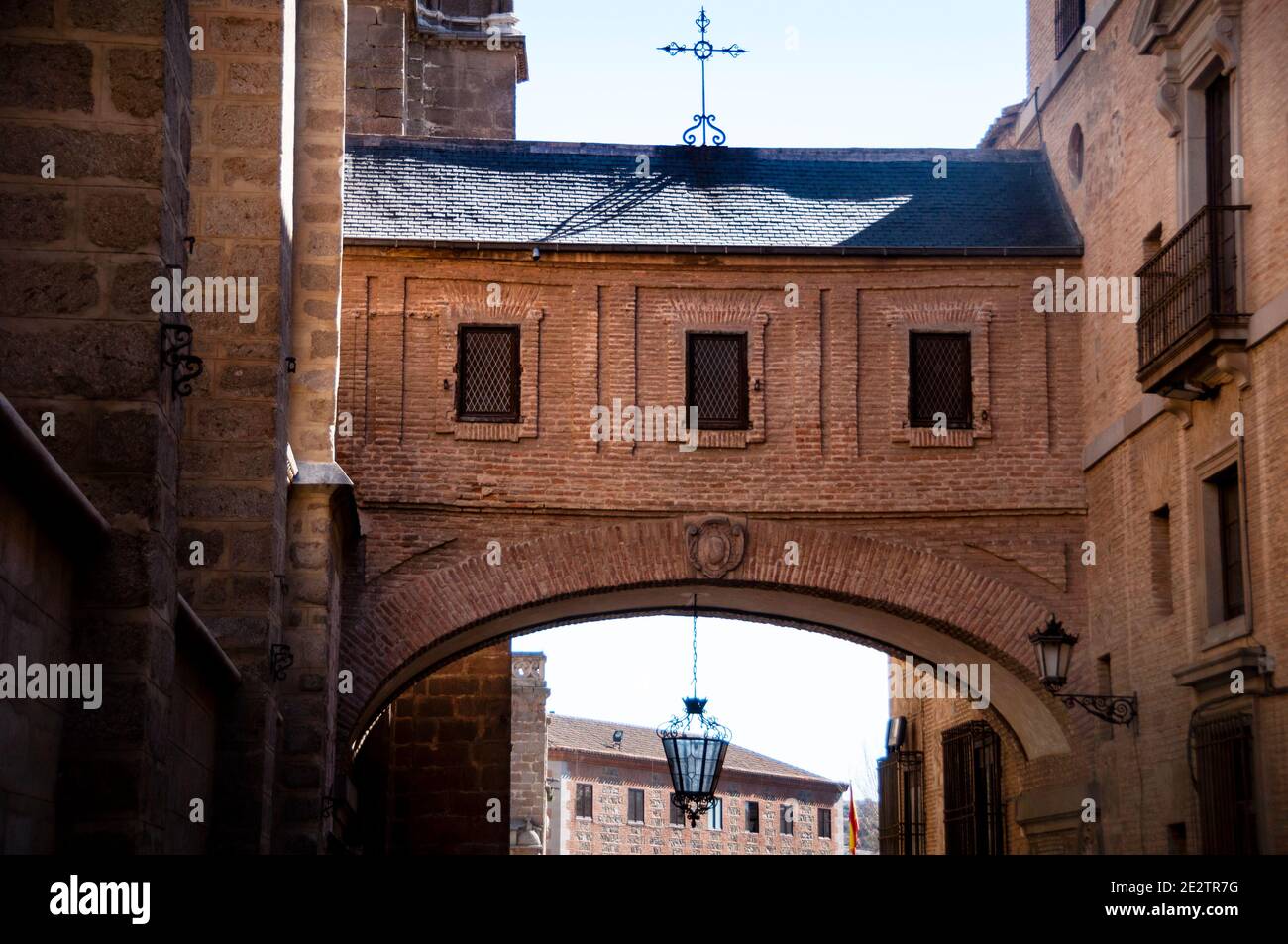 A delicate Christian iron cross atop the Toledo Cathedral Arch brick