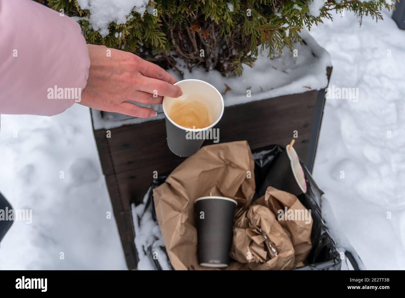 Used coffee cup in the trash can female hand throws out trash, taking care of nature Stock Photo