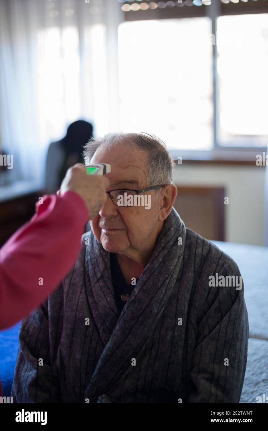 Senior man during temperature check for Covid-19 at home Stock Photo