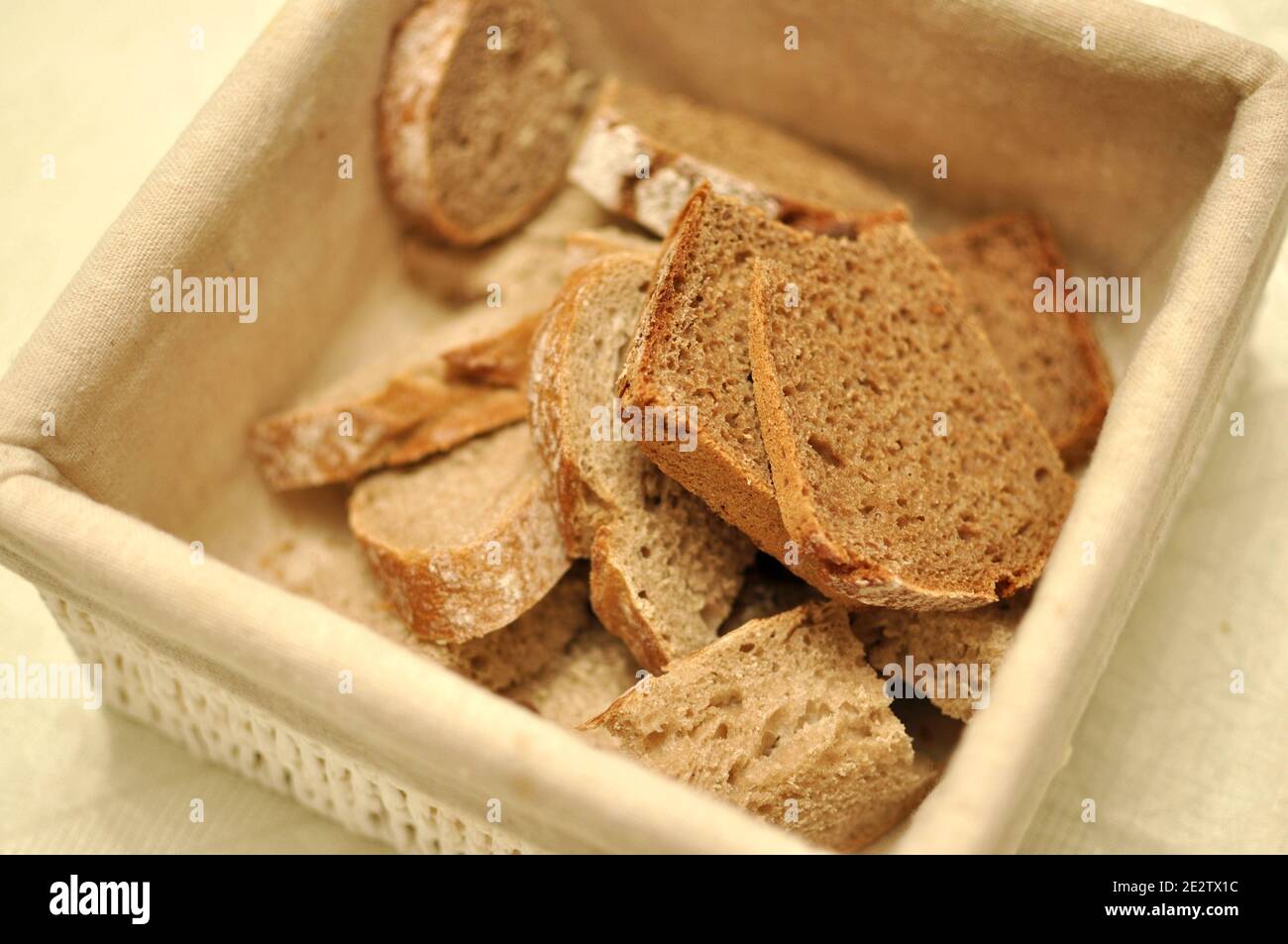 Close up of a beige textile basket full of healthy brown cereals bread Stock Photo