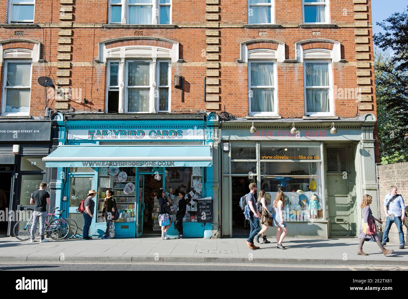 Earlybird Cards shop with people including cyclist talking outside and people passing. A busy urban street scene Stoke Newington Church Street London Stock Photo