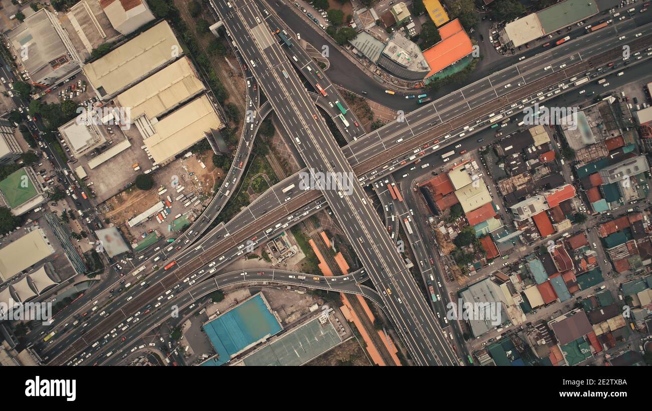 Top down of cross road traffic with cars, trucks, vehicles in aerial view. Downtown of Manila city with colorful buildings roofs at roadside. Philippines urban lifestyle with local journey Stock Photo