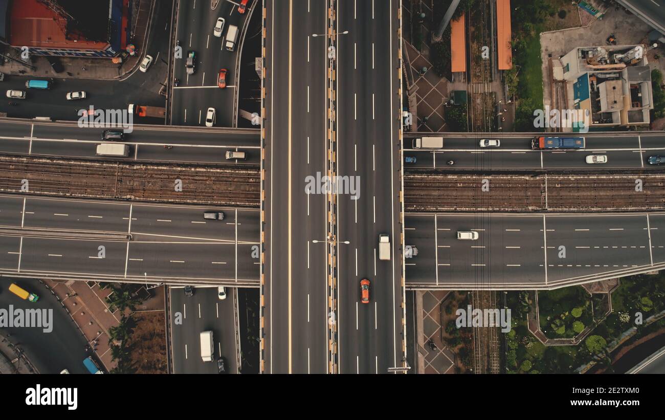 Top down cross traffic highway with cars, trucks aerial. Urban transportation at bridge road at metropolis city of Manila, Philippines, Asia. Cinematic cityscape of downtown freeway drone shot Stock Photo