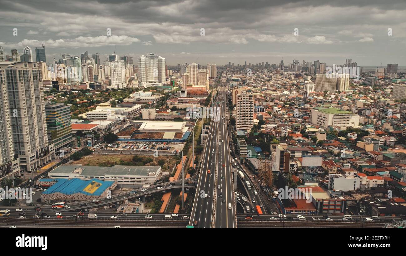 Traffic highway at modern skyscrapers aerial. Epic cityscape with streets along road. Block buildings and cottages at cloudy summer day. Downtown local transportation at Manila city, Philippine Stock Photo
