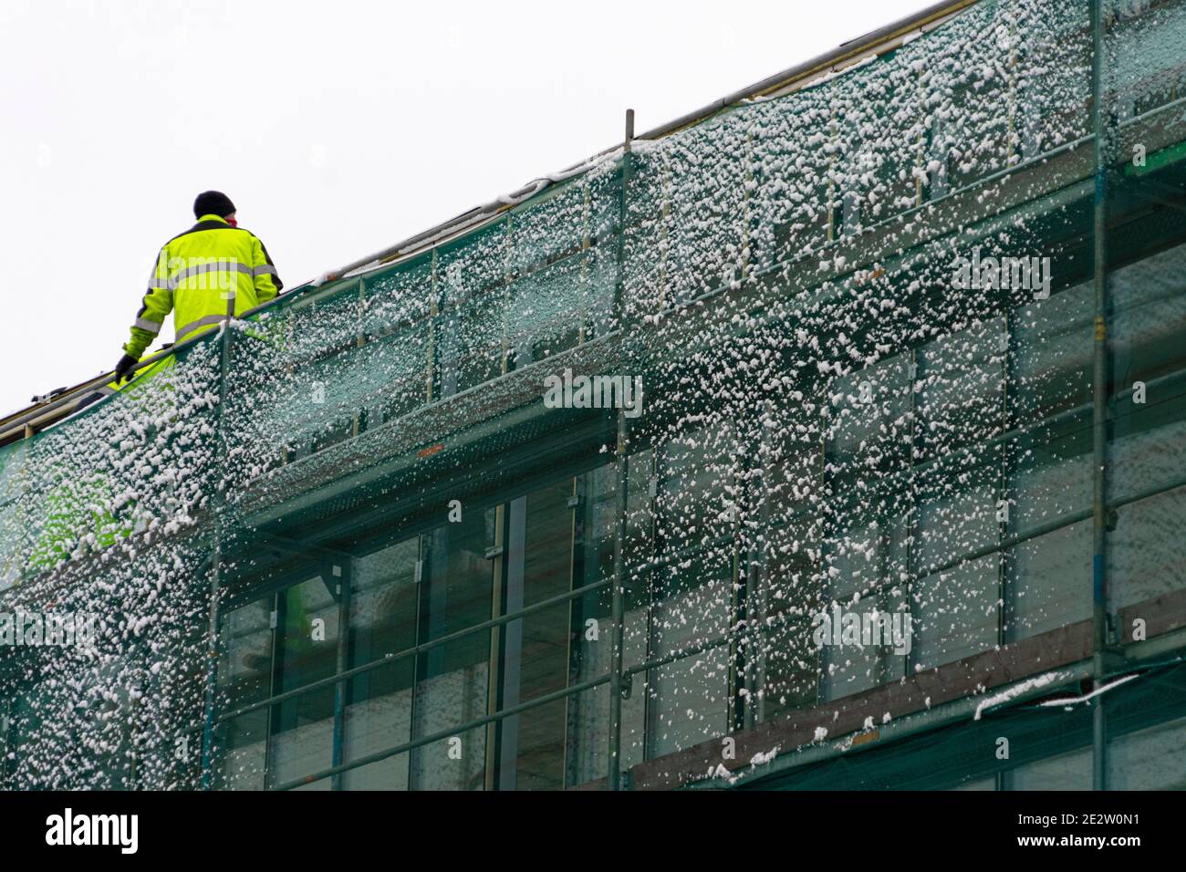 Construction worker works on new building with scaffolding in winter ...