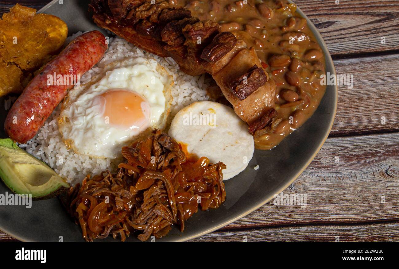 Bandeja paisa, typical dish of Colombia. It consists of chicharrón (fried pork belly), black pudding, sausage, arepa, beans, fried banana, avocado egg Stock Photo