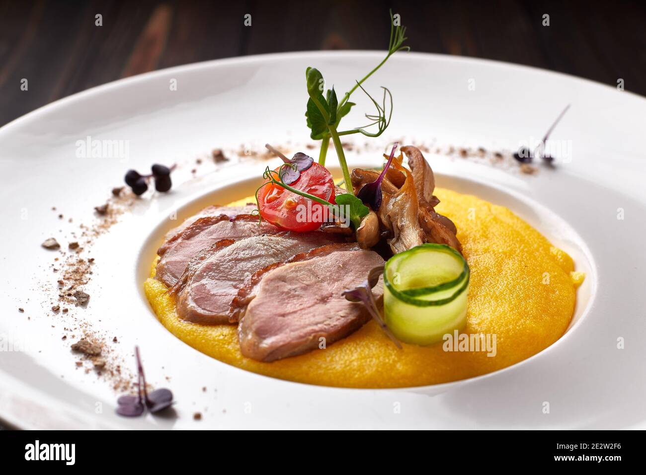 Corn porridge with meat and mushrooms, on a white plate. polenta, ugali, Banosh, mamaliga Stock Photo