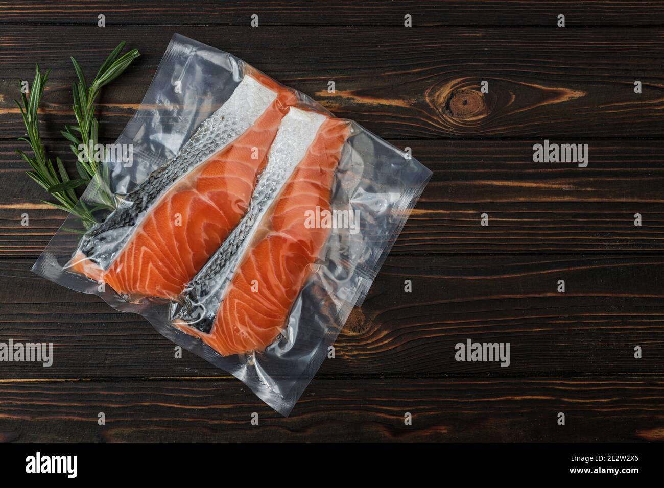 Vacuumpacked fish, trout, salmon on a wooden board. Top view Stock