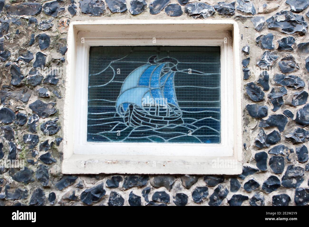 A stained glass window depicting a ship on the flint wall of York Gate House in Broadstairs, Isle of Thanet, Kent, United Kingdom Stock Photo